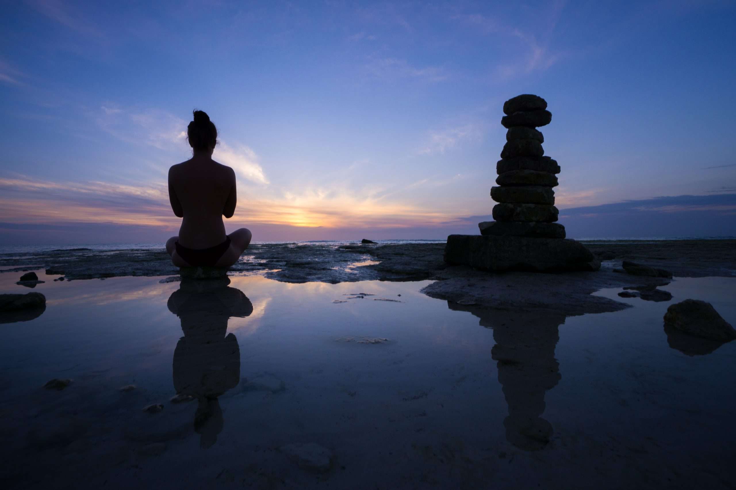 Silhouette of a girl meditated against beautiful sunset on the sea