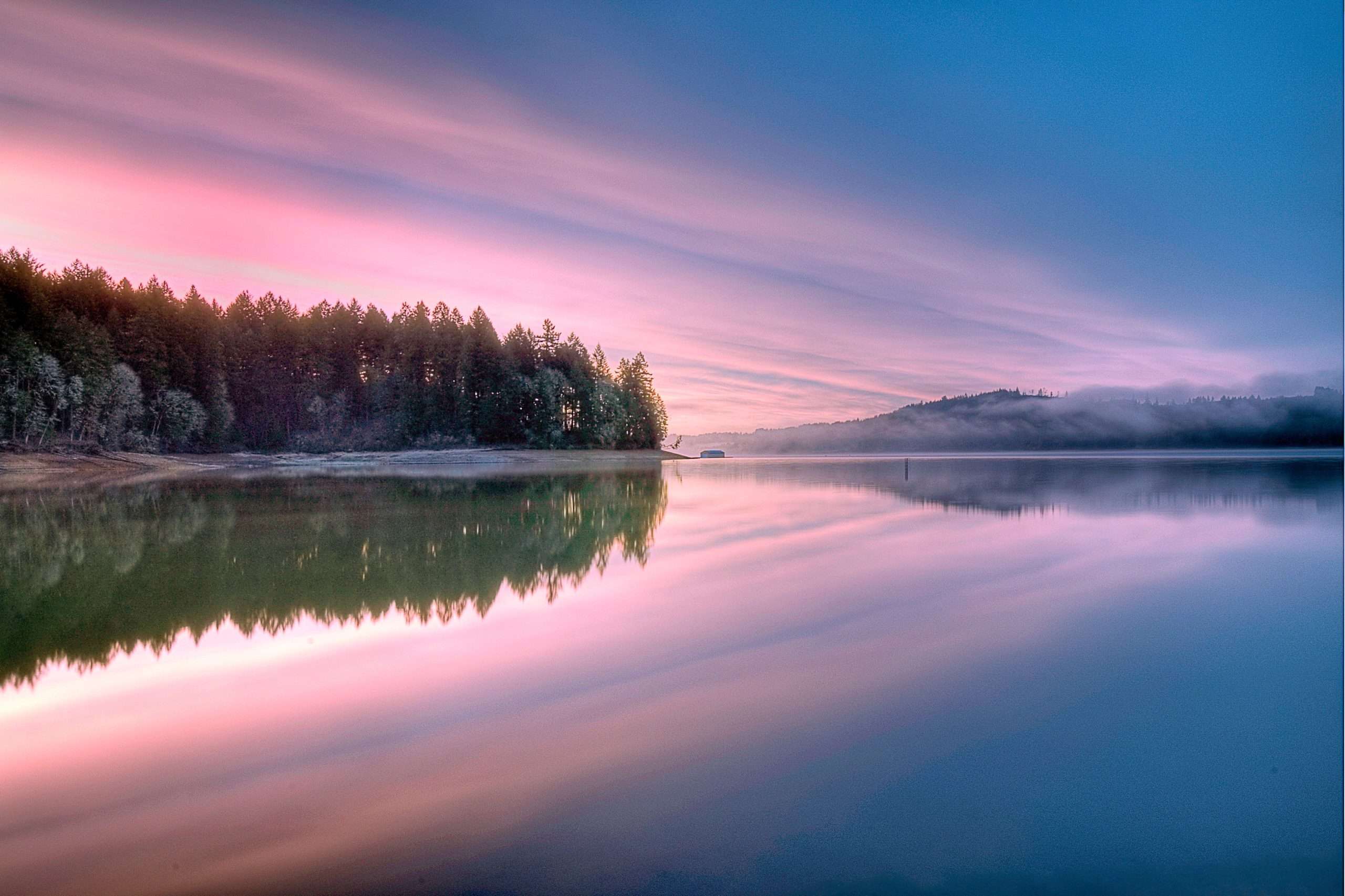 Tranquil water reflects a pink sunset sky