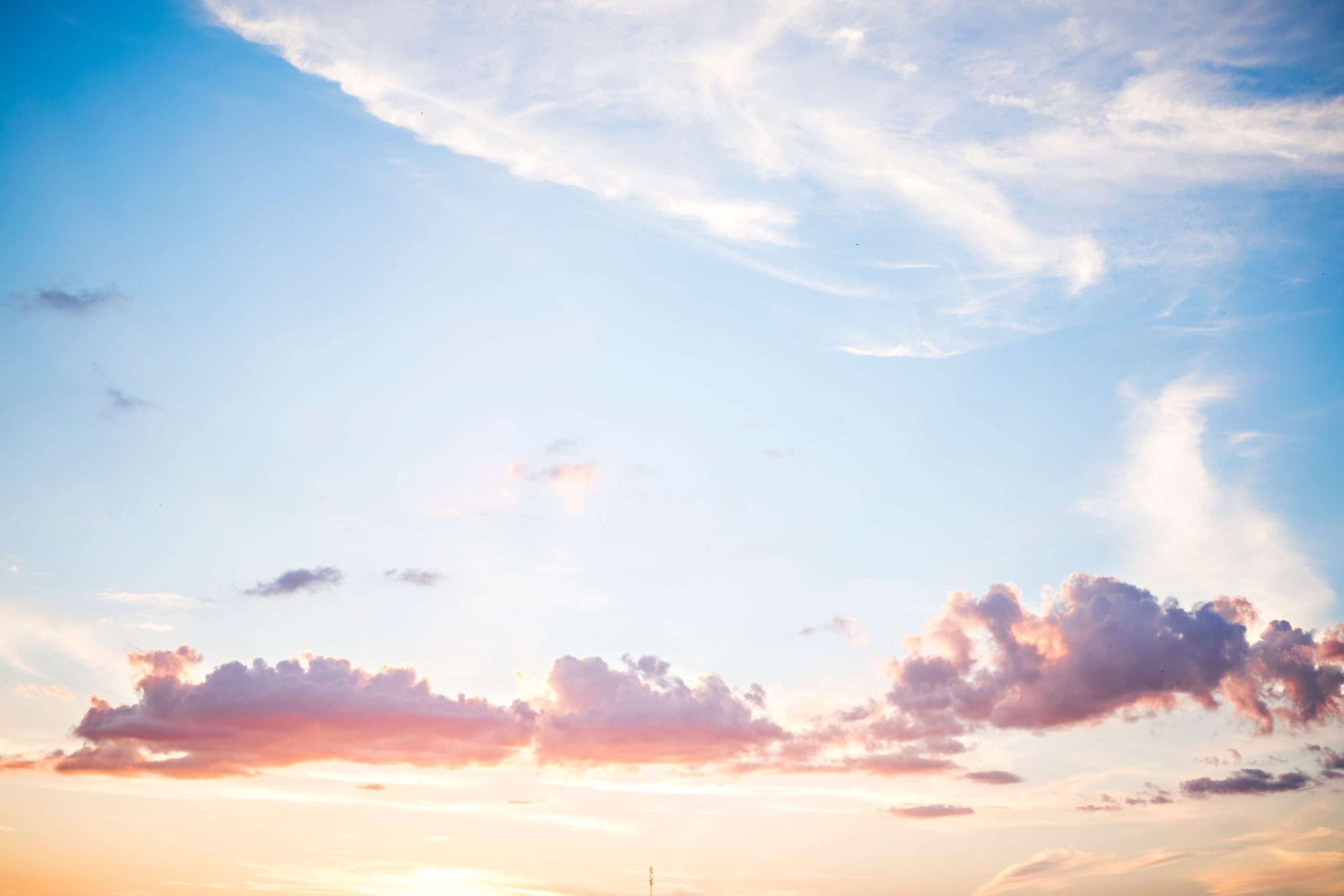 Beautiful pastel blue sky with fluffy clouds at sunset. Wallpaper natural background.